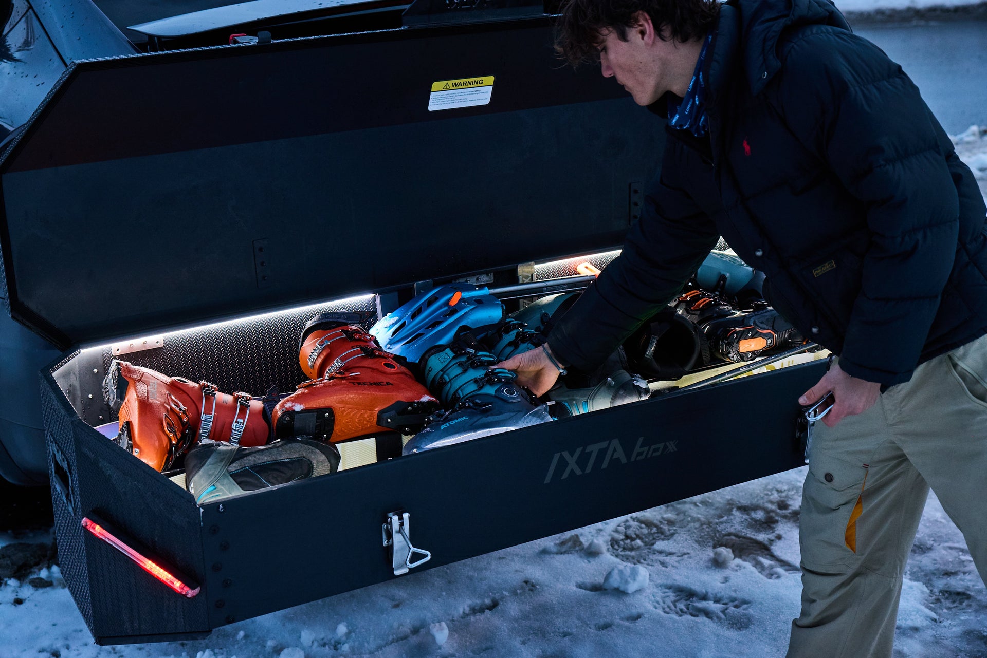 Coffre IXTAbox ouvert avec équipement de ski et gants dans un cadre enneigé