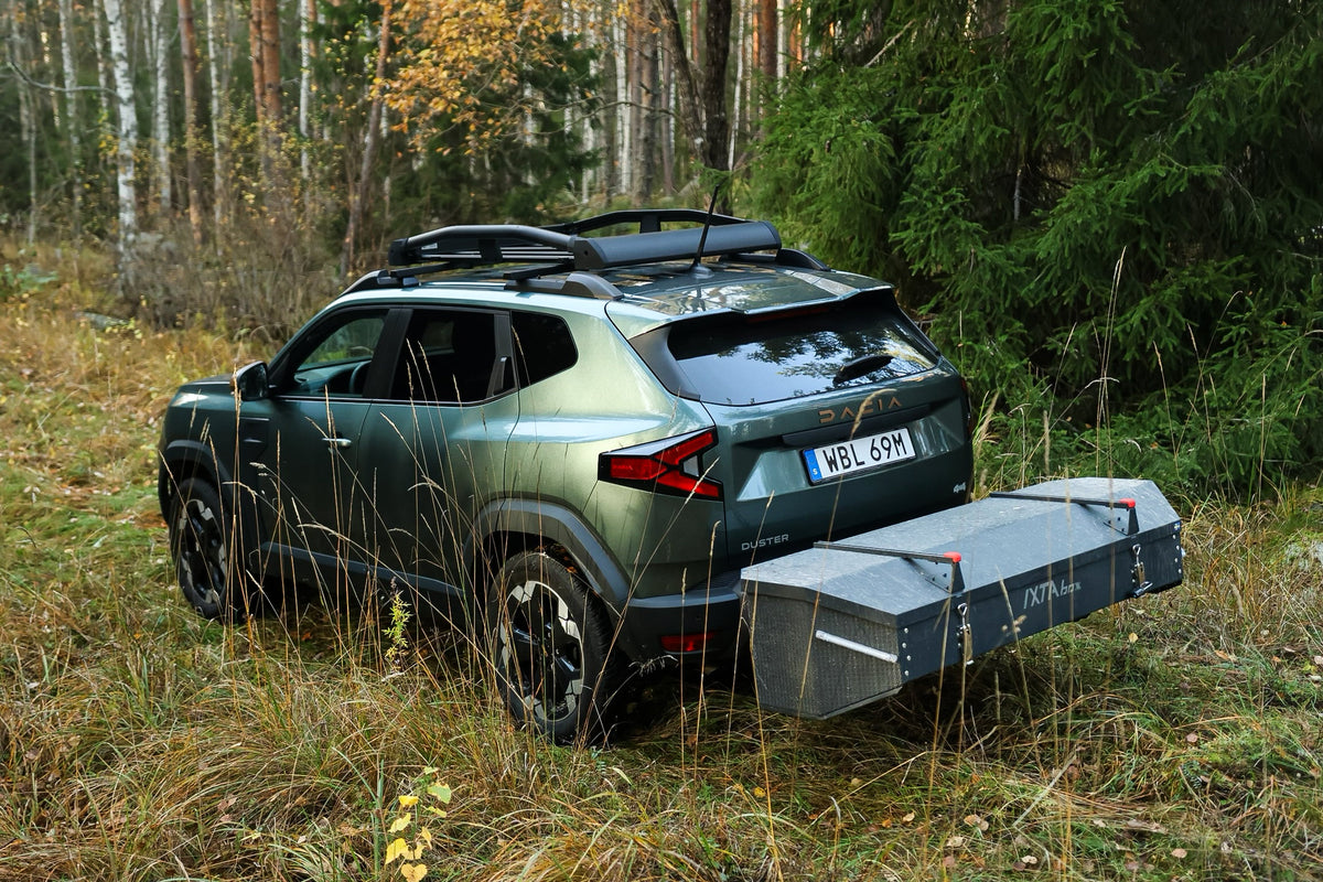 Dacia Duster with an IXTAbox rear cargo box mounted on the tow bar, parked on a forest track